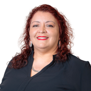 A woman with curly red hair and a black shirt smiles against a plain background.