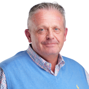 Man in blue sweater and checkered shirt, smiling at camera against white background.
