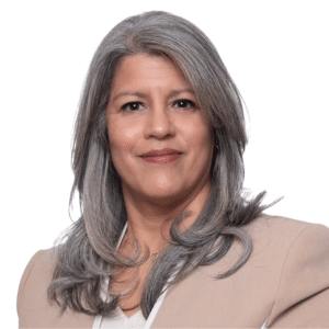 A woman with gray hair wearing a beige blazer against a white background.