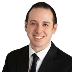 A smiling man in a suit and tie against a white background.