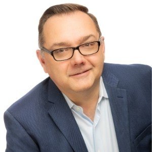 Headshot of Martyn Etherington in a blue suit jacket against a white background.