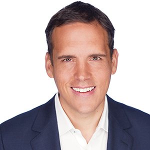 A person smiling in a suit on a white background.
