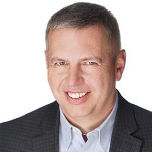 A person smiling in a professional attire against a white background.