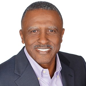 A man in a suit smiling against a white background.